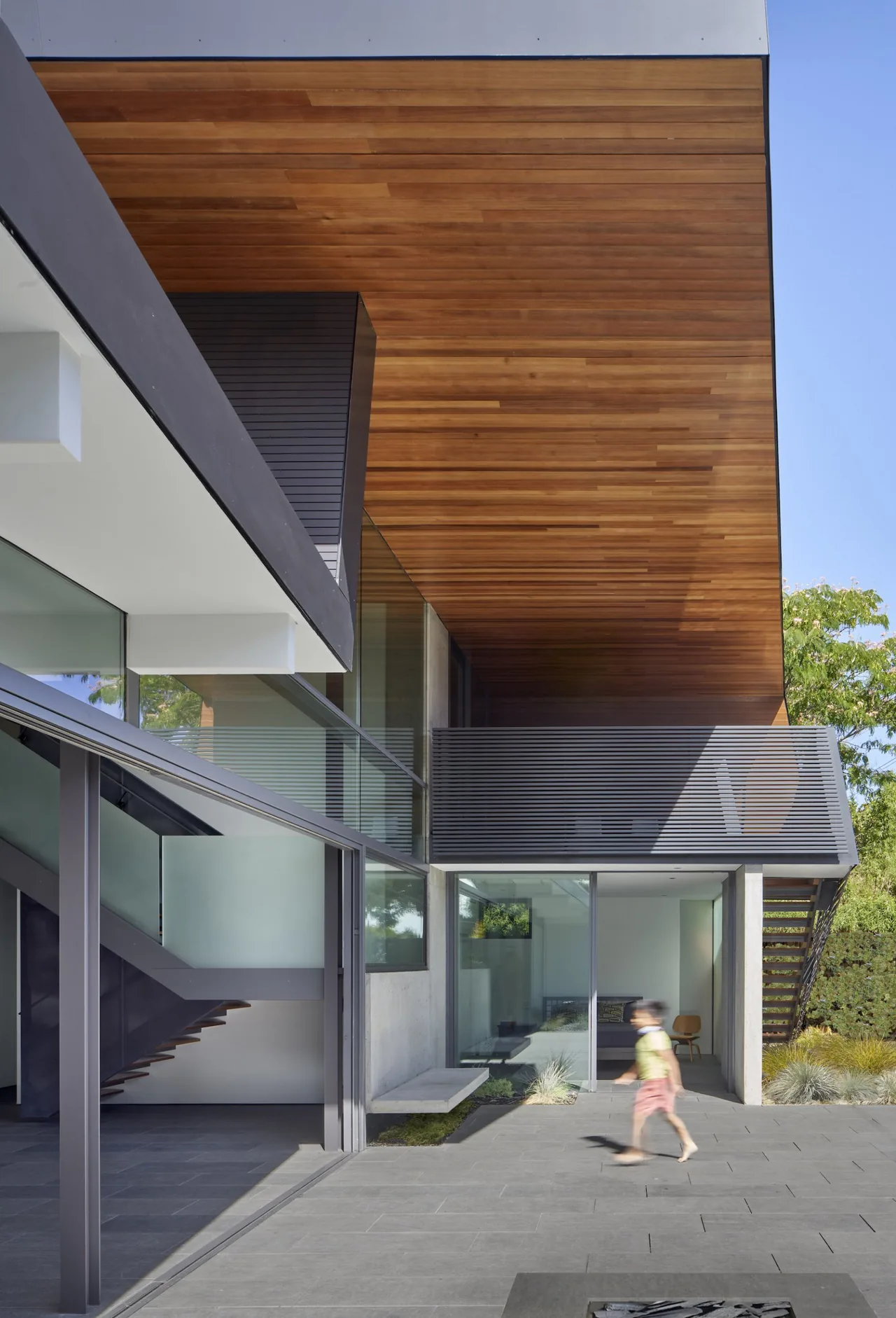 Edgewood House features an outdoor patio with a wood soffit ceiling and gray exterior by Terry & Terry Architecture.