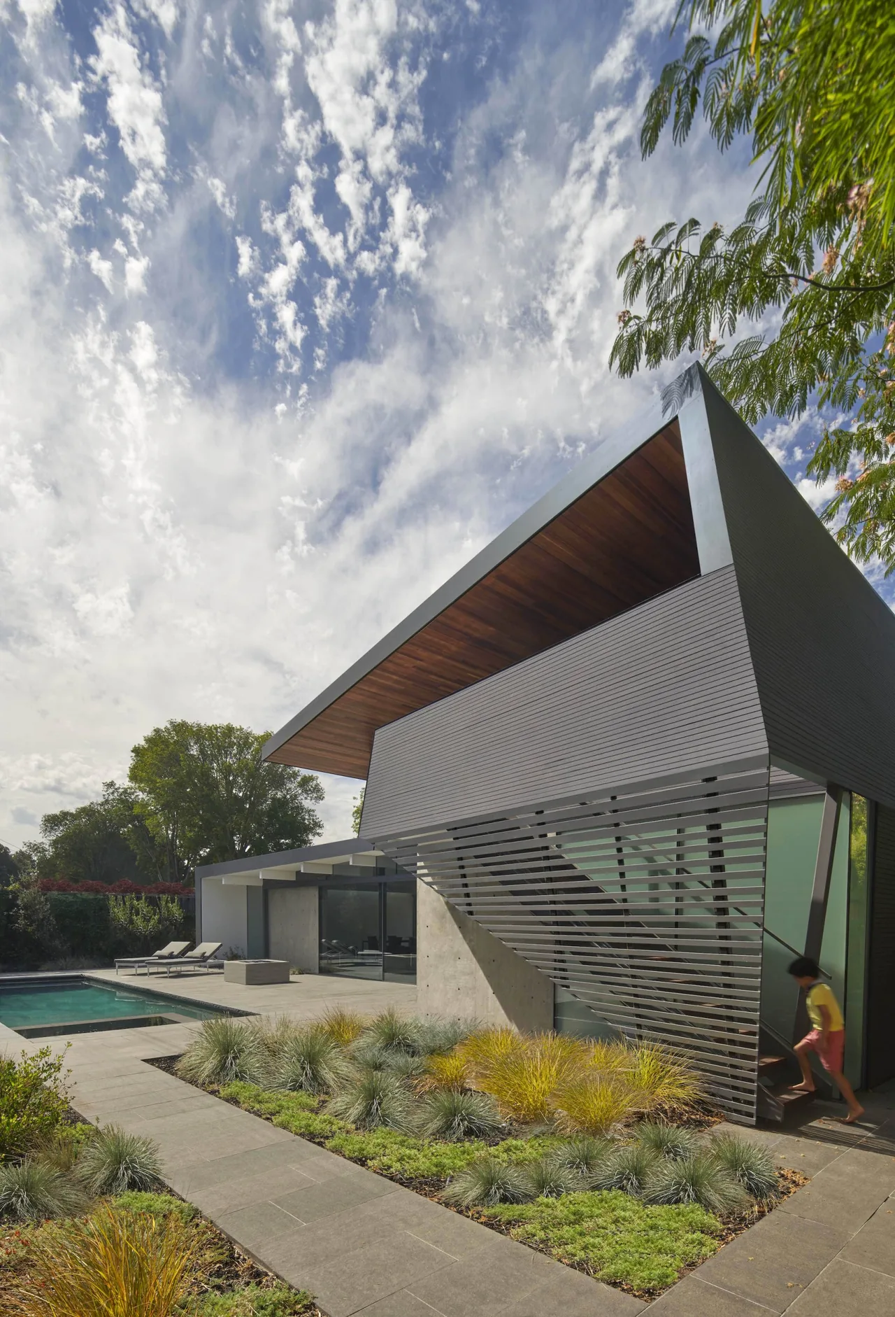 Edgewood House features a cantilevered roof and slatted exterior wall near a pool and landscaped patio area.