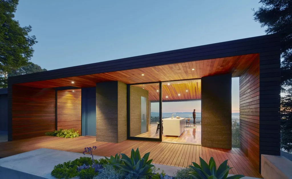 The Skyline House features wood siding and a recessed deck with city views, designed by Terry & Terry Architecture.
