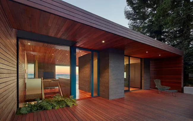 Skyline House features wood siding and ceiling, with large glass doors opening to an expansive covered outdoor deck.