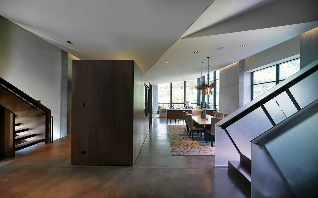 The Diagonal House features a dining space with black window frames and polished concrete floors, designed by Stephen Dynia Architects.