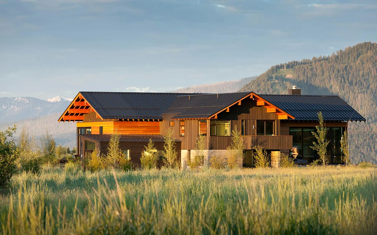 Diagonal House by Stephen Dynia Architects features dark wood paneling, black standing seam metal roofs, and a natural mountain setting.