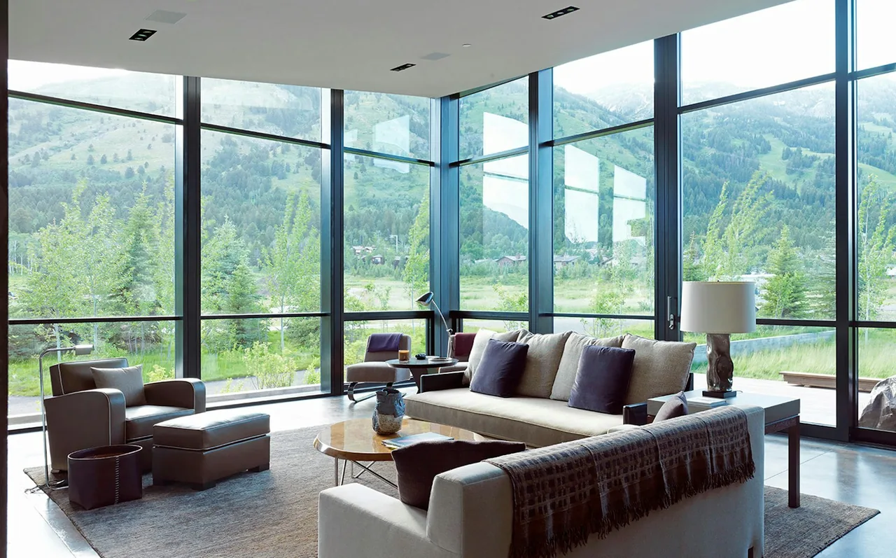 Living room of Diagonal House with expansive floor-to-ceiling windows showcasing mountain views.