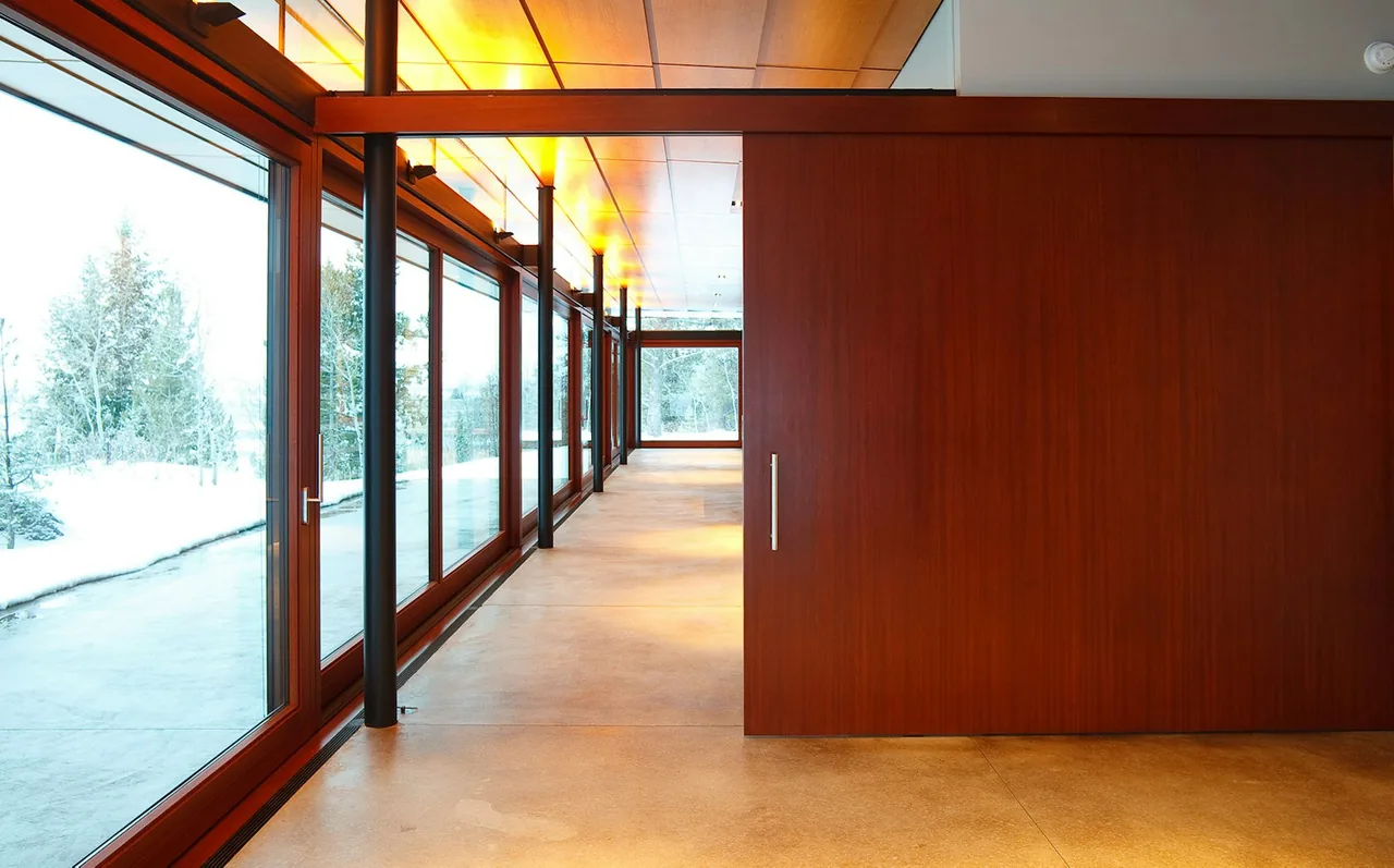 Interior corridor of Lost Creek Cabin featuring floor-to-ceiling glazing and wood-paneled ceiling.