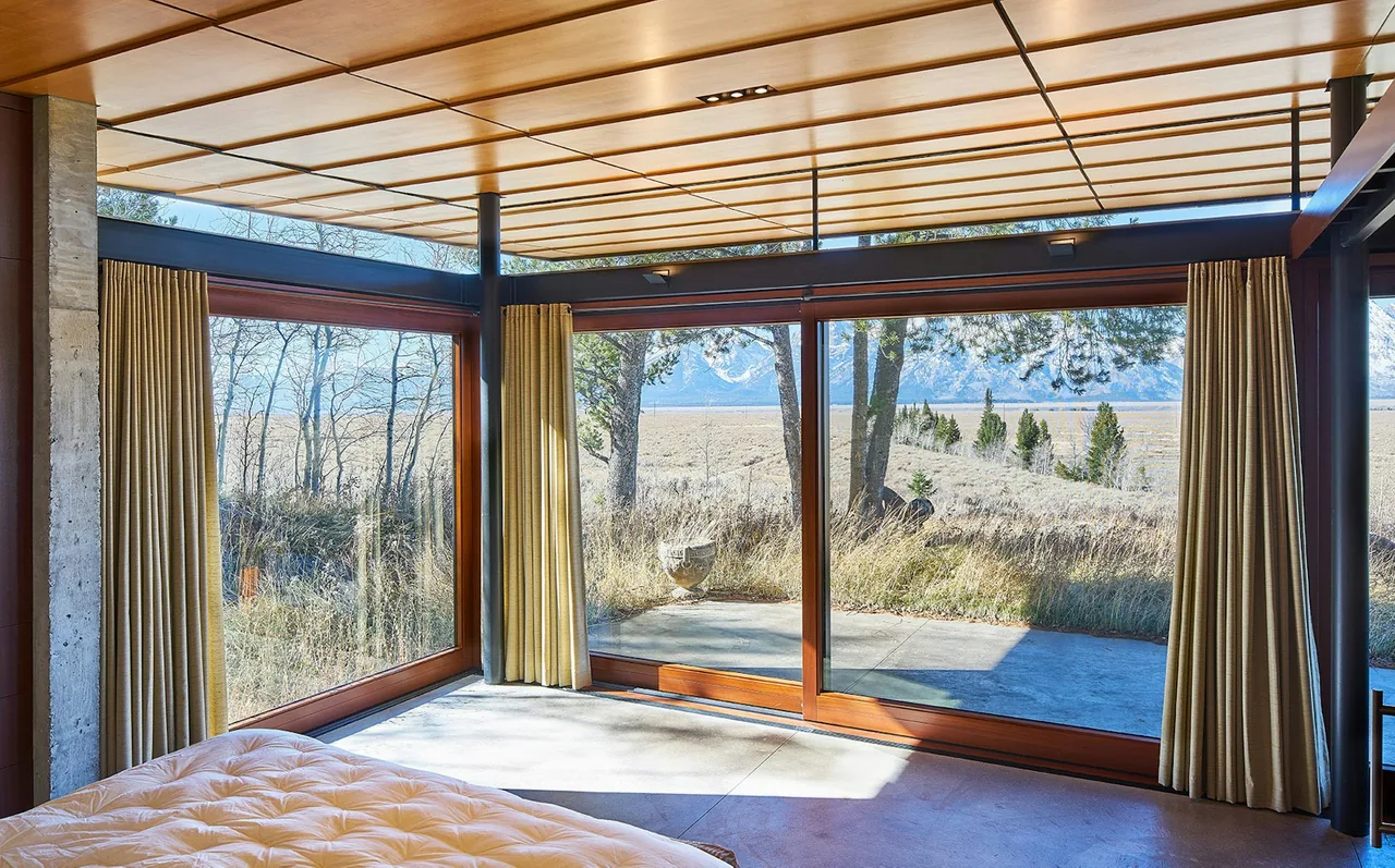 Lost Creek Cabin bedroom with large sliding glass door and floor-to-ceiling windows showcasing mountain and forest views.