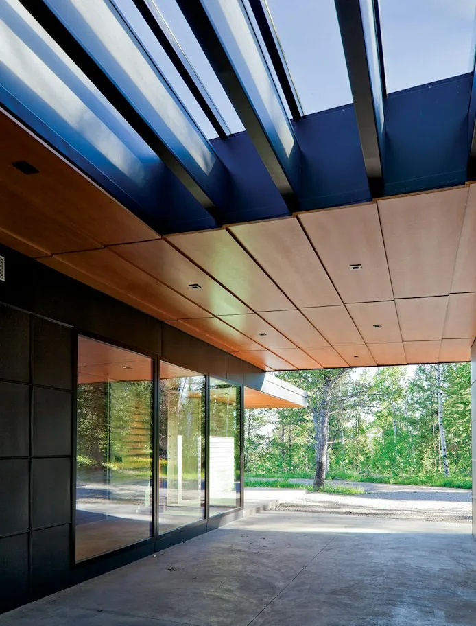 Exterior area of Lost Creek Cabin features a wood-paneled ceiling and concrete floor with large glass windows.