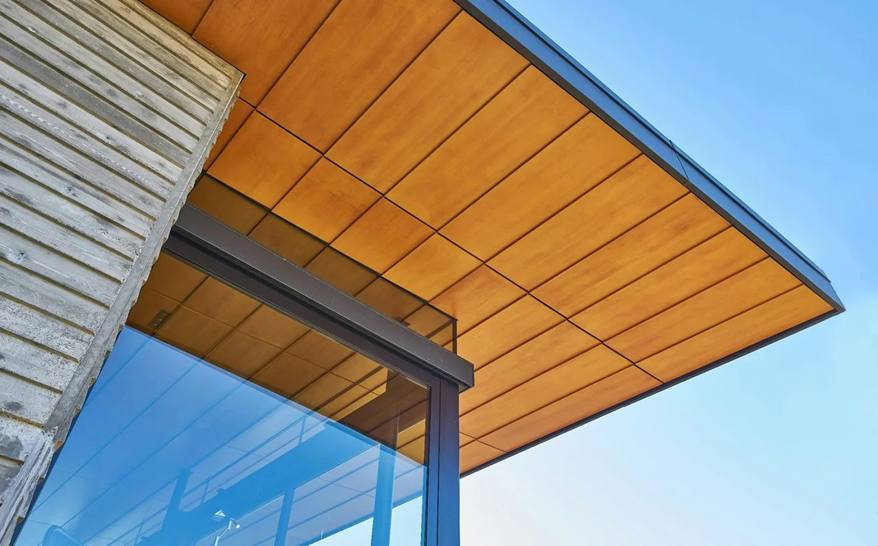 The Lost Creek Cabin features an overhanging wood-paneled roof with black window frames and large glass doors.