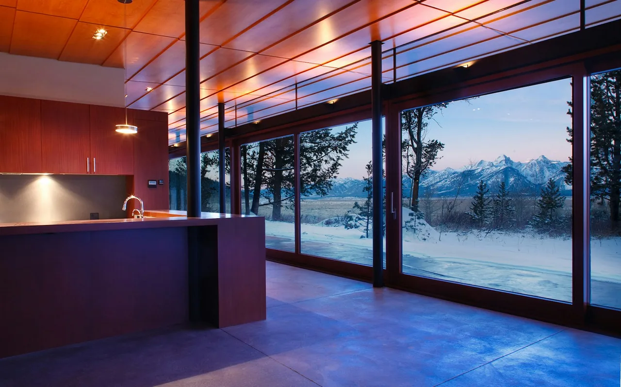 Lost Creek Cabin kitchen features a wood-paneled ceiling and large glass walls with mountain views.
