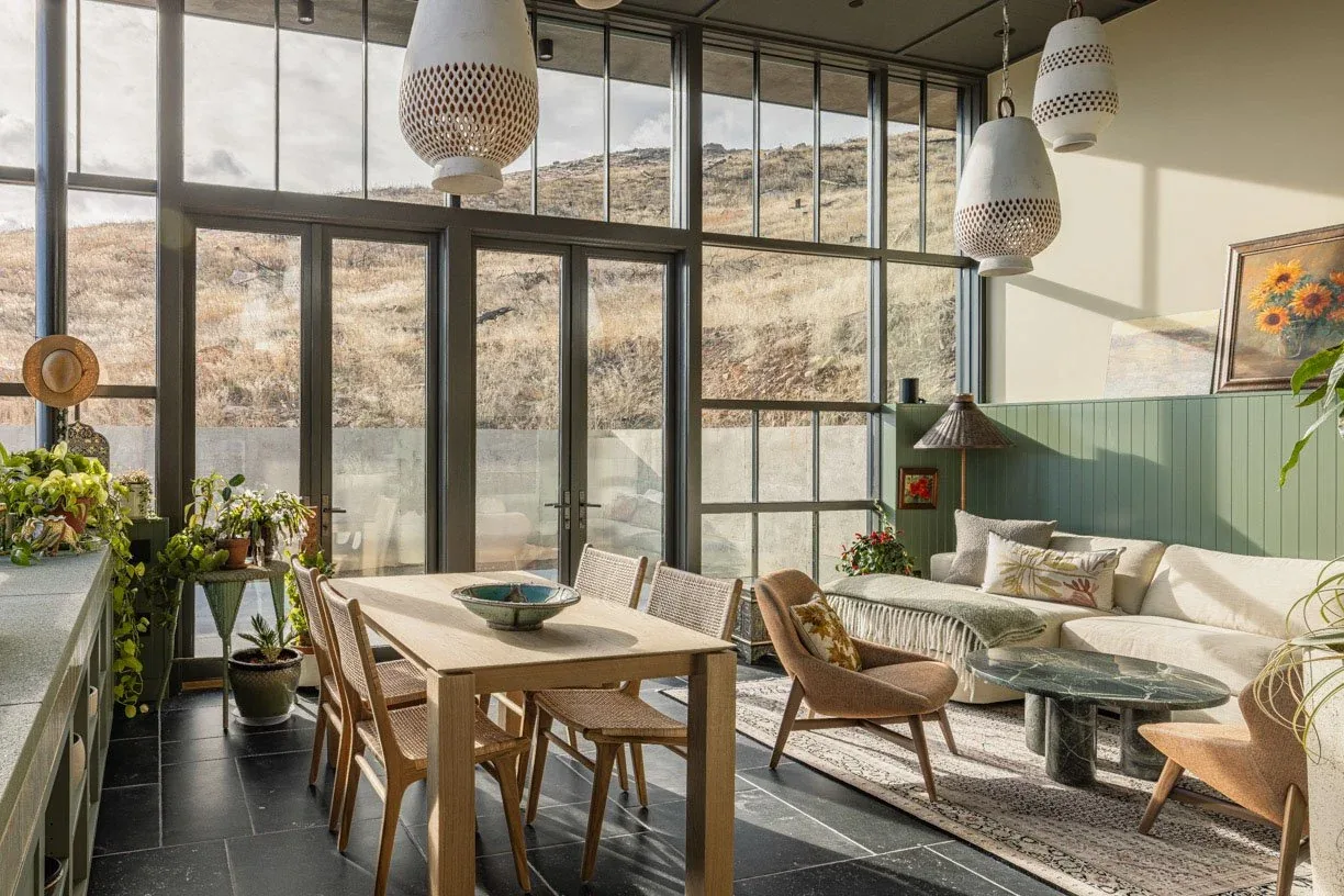 The Boulder Mountain Residence living and dining area features floor-to-ceiling glazing and natural wood furniture.
