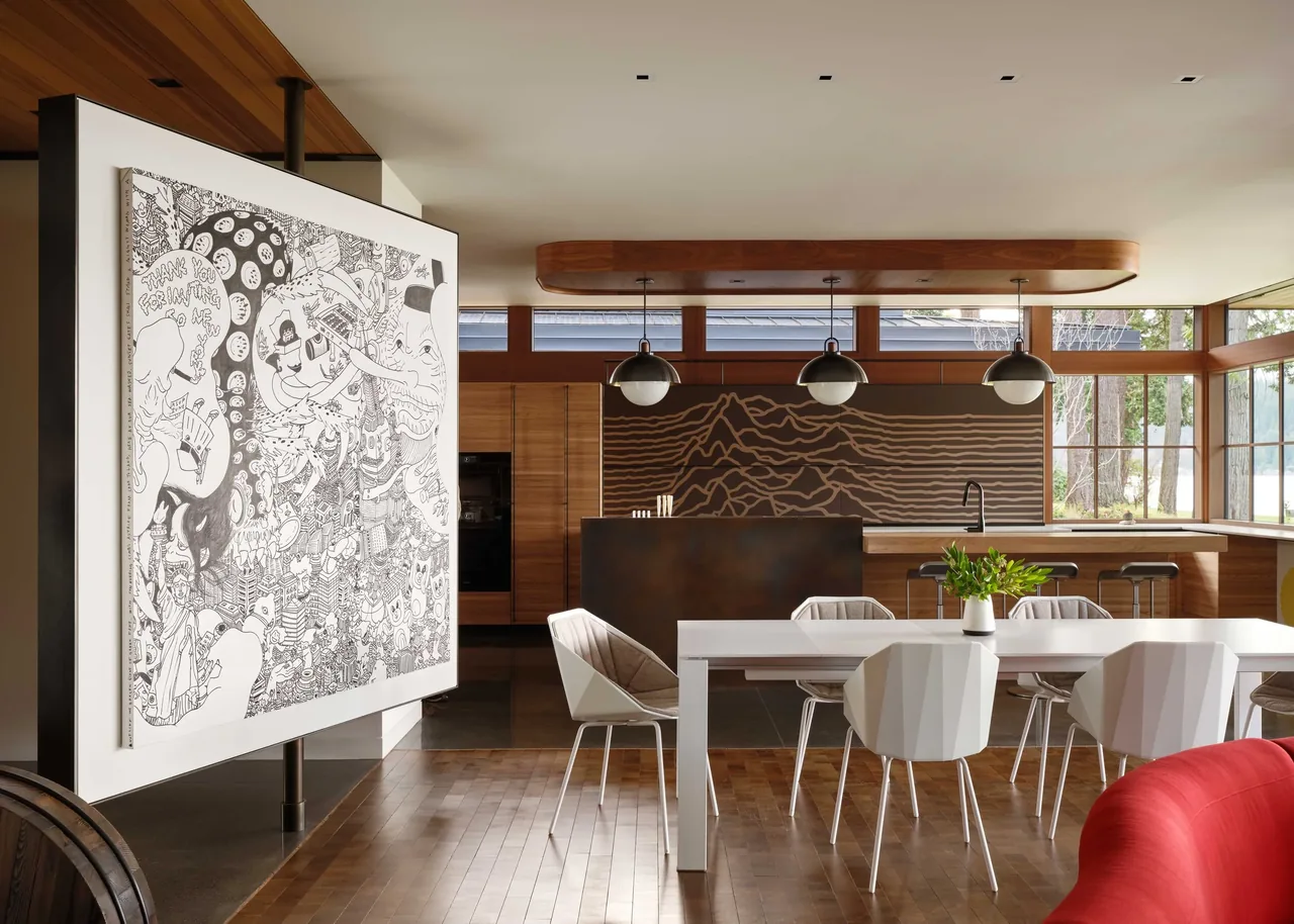 Open kitchen and dining area feature wood cabinetry, distinctive wall art, and large windows bringing in natural light.