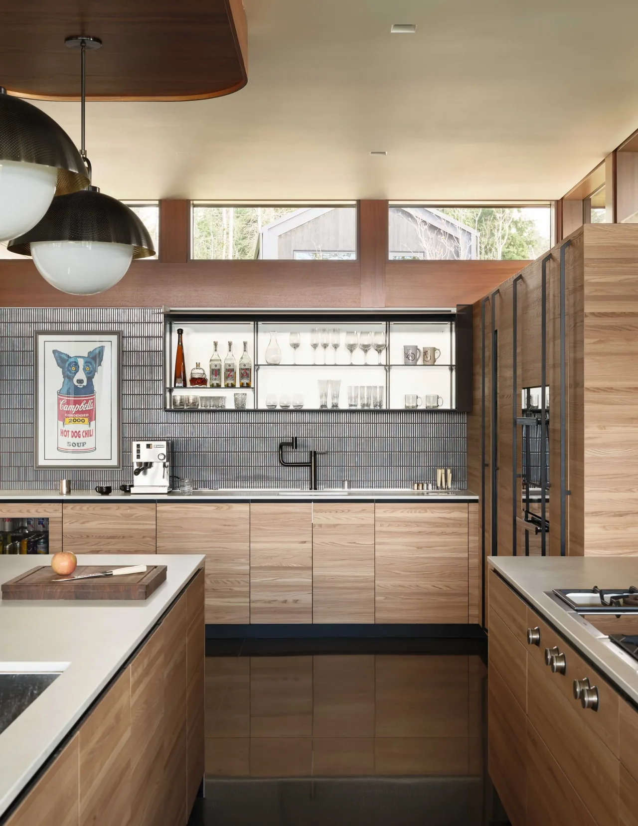 Kitchen in Gamer HQ with wood cabinets, black tile backsplash, and a built-in glassware shelving unit above the sink.