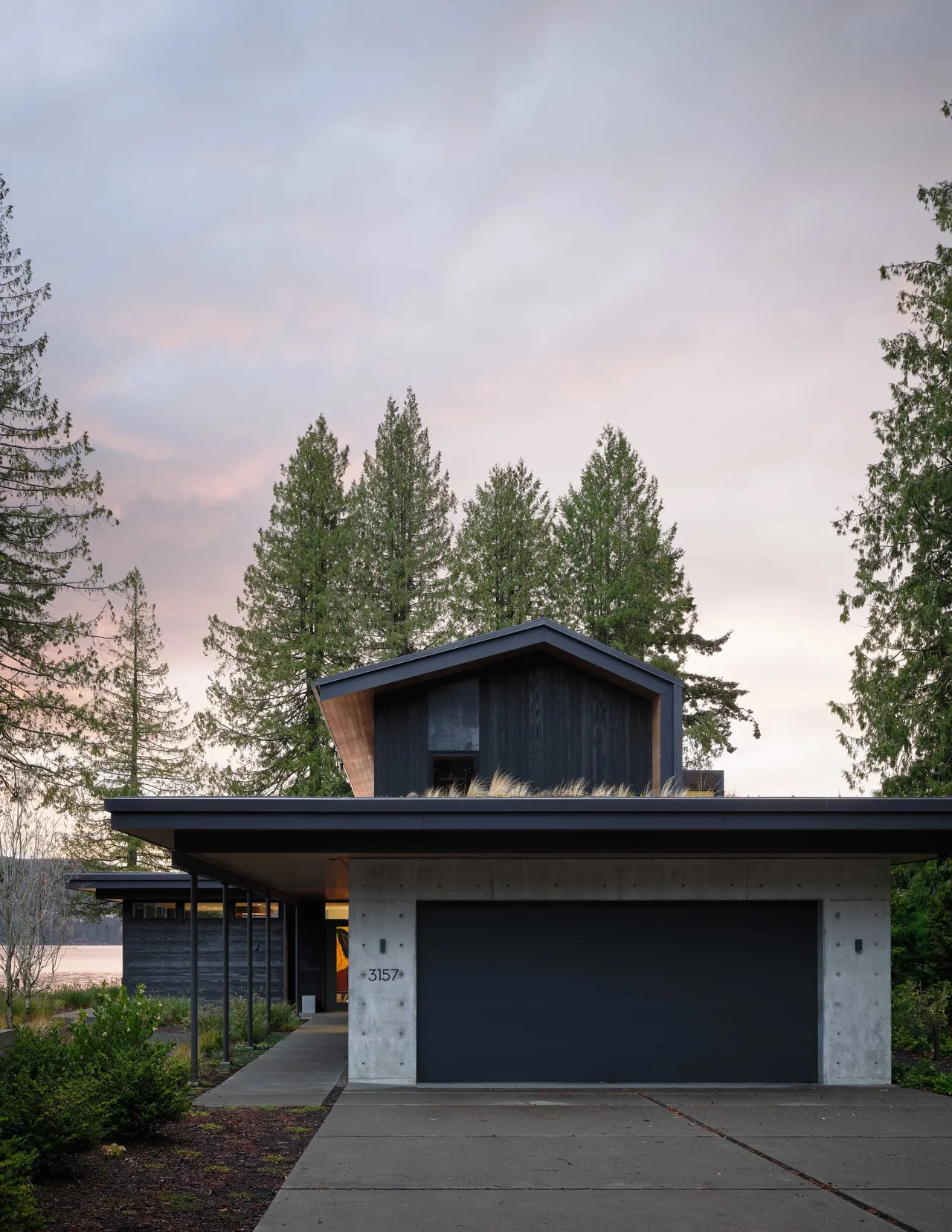 Gamer HQ features dark wood siding and a concrete garage with a flat roof and a two-story design by skB Architects.