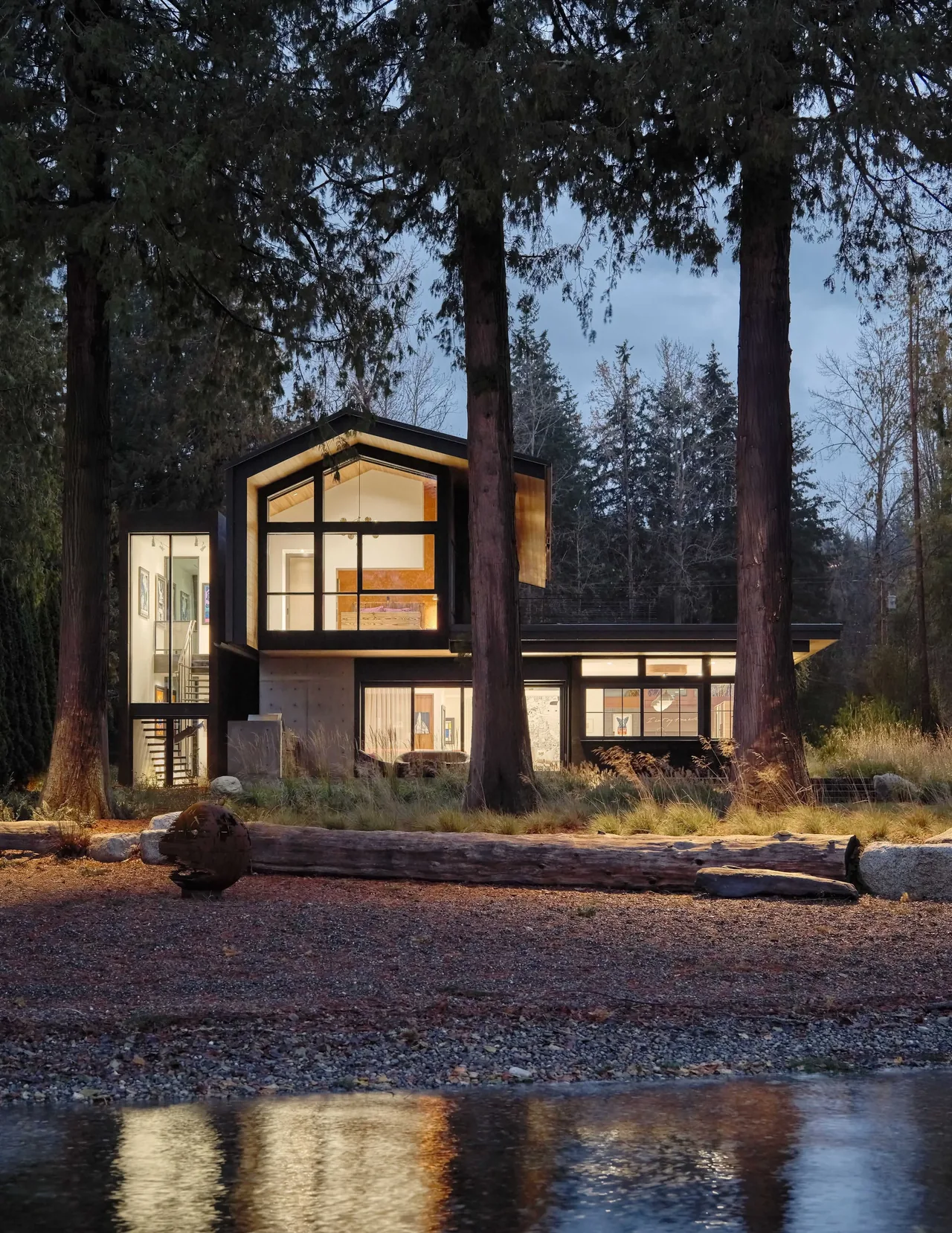 Gamer HQ by skB Architects features dark wood siding and large picture windows in a forested setting.