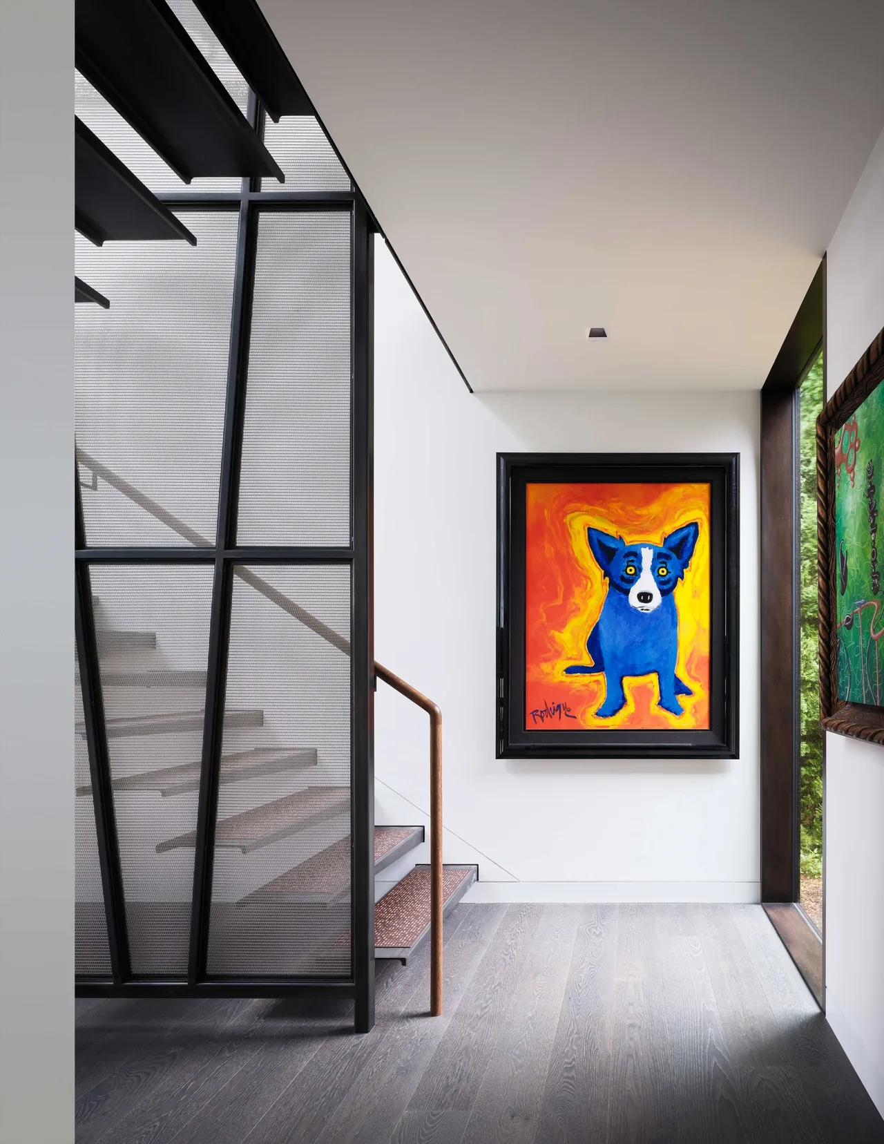 Stairwell with black mesh railing and vibrant blue dog painting on gallery wall.