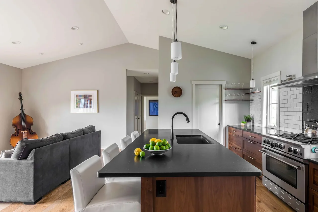 The Roses Lake Residence kitchen features a black countertop island with seating, white subway tile backsplash, and dark wood lower cabinets.