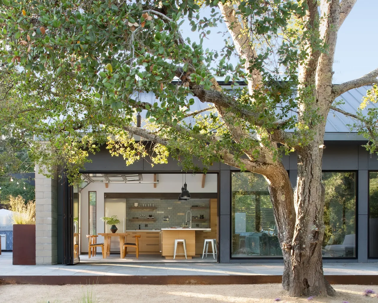 The Sonoma Farmhaus features folding glass doors that open a wood-toned kitchen and dining area to the outdoor seating space.