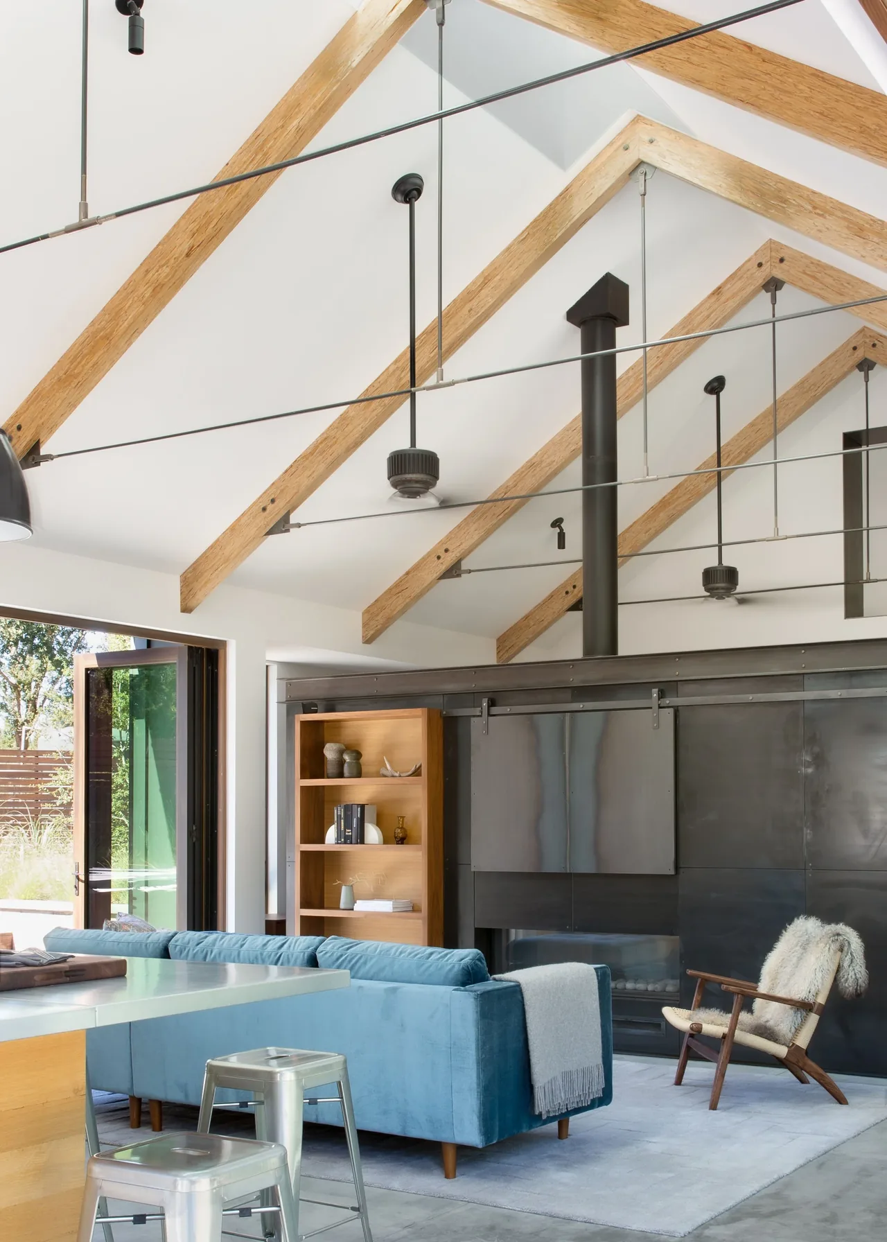 Living room with vaulted ceiling features exposed wood beams and a black metal fireplace wall.