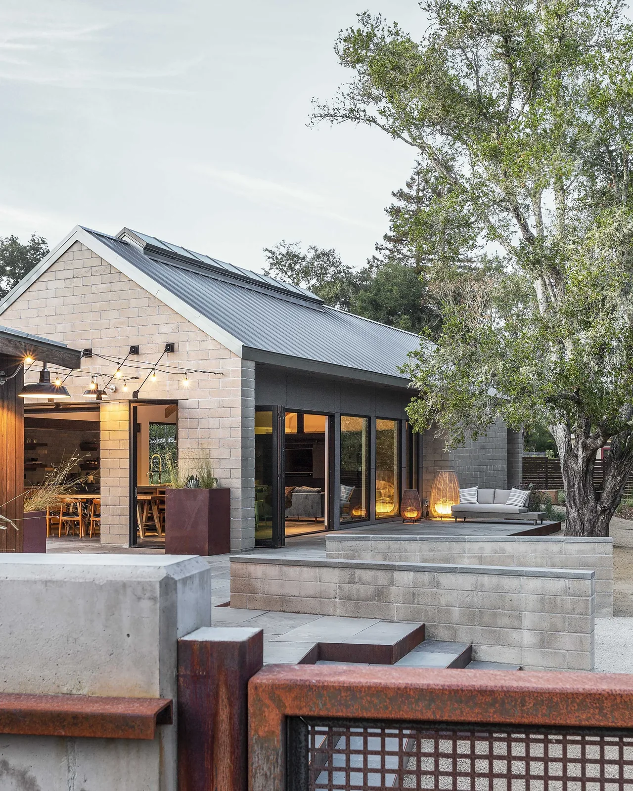 Sonoma Farmhaus features a metal gable roof, folding glass doors, and an outdoor seating area with ambient string lighting.