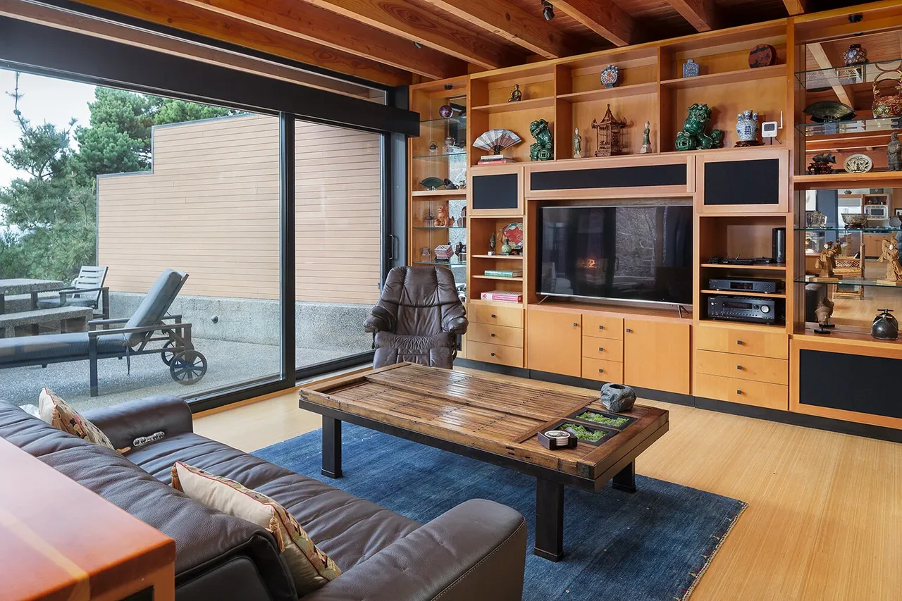 Living room with leather sofa, built-in wooden shelving, and sliding glass doors opening to outdoor seating at Horizon Hill House.