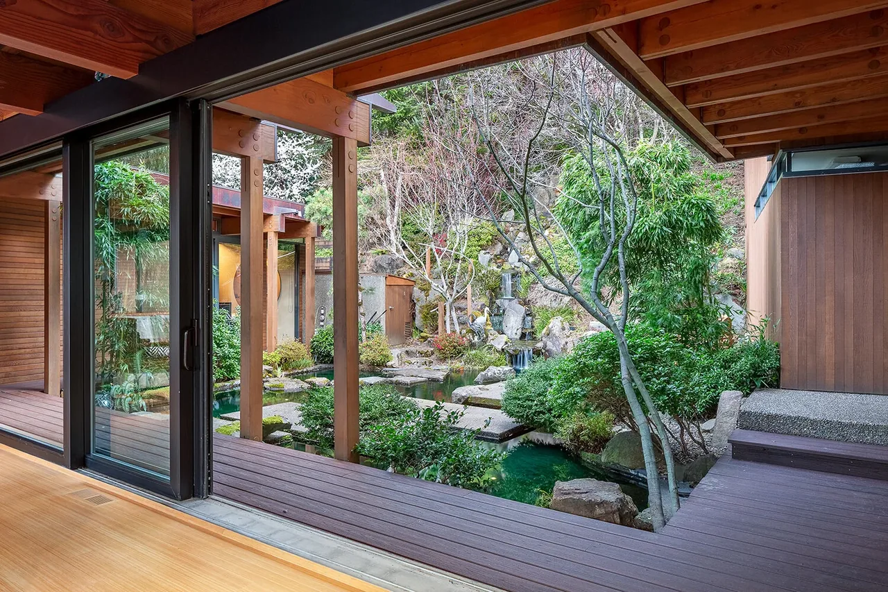 The Horizon Hill House features a courtyard with a pond, waterfall, and lush greenery, visible through floor-to-ceiling sliding glass doors.