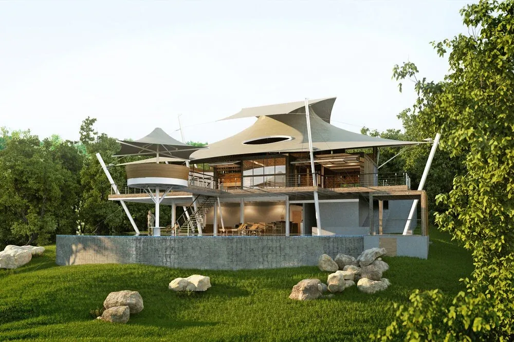Modern two-story home with tensioned shade sails, metal cable supports, and a wooden deck surrounded by green landscaping.