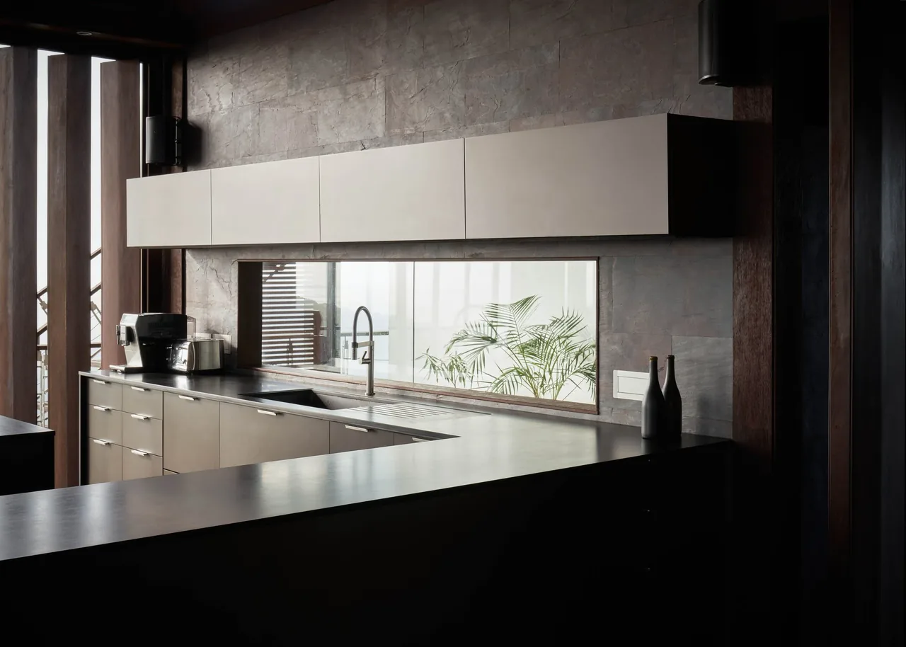 Modern kitchen in the SAIL HOUSE project with a horizontal window and minimalist cabinetry.