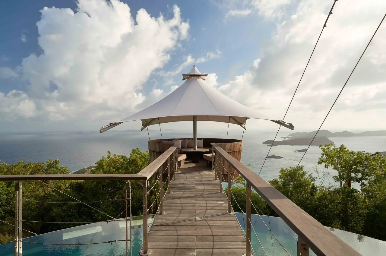 Triangular shade sail covers a circular outdoor seating area at the Sail House with ocean views.