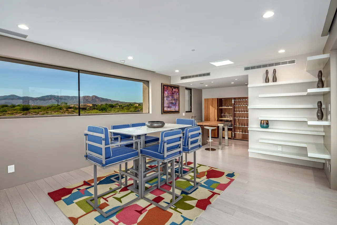 Dining space with modern furniture and a large horizontal window overlooking the desert landscape in the Kim Residence by Tate Studio Architects.