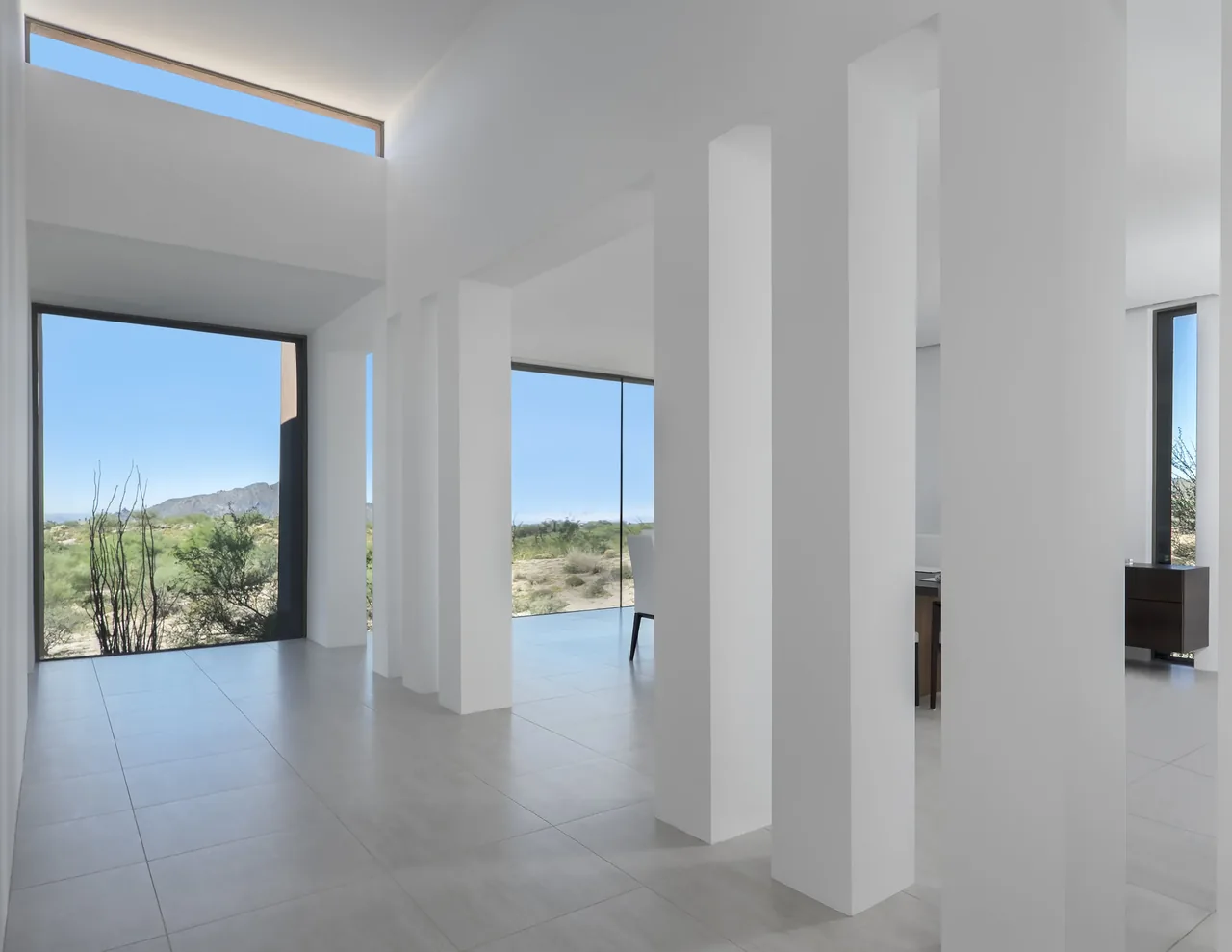 Modern interior with white columns and expansive windows showcasing desert views at Kim Residence.