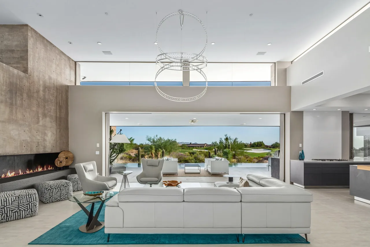 The Kim Residence living area features a concrete fireplace, floor-to-ceiling glazing, and a seamless indoor-outdoor transition with sliding glass doors.