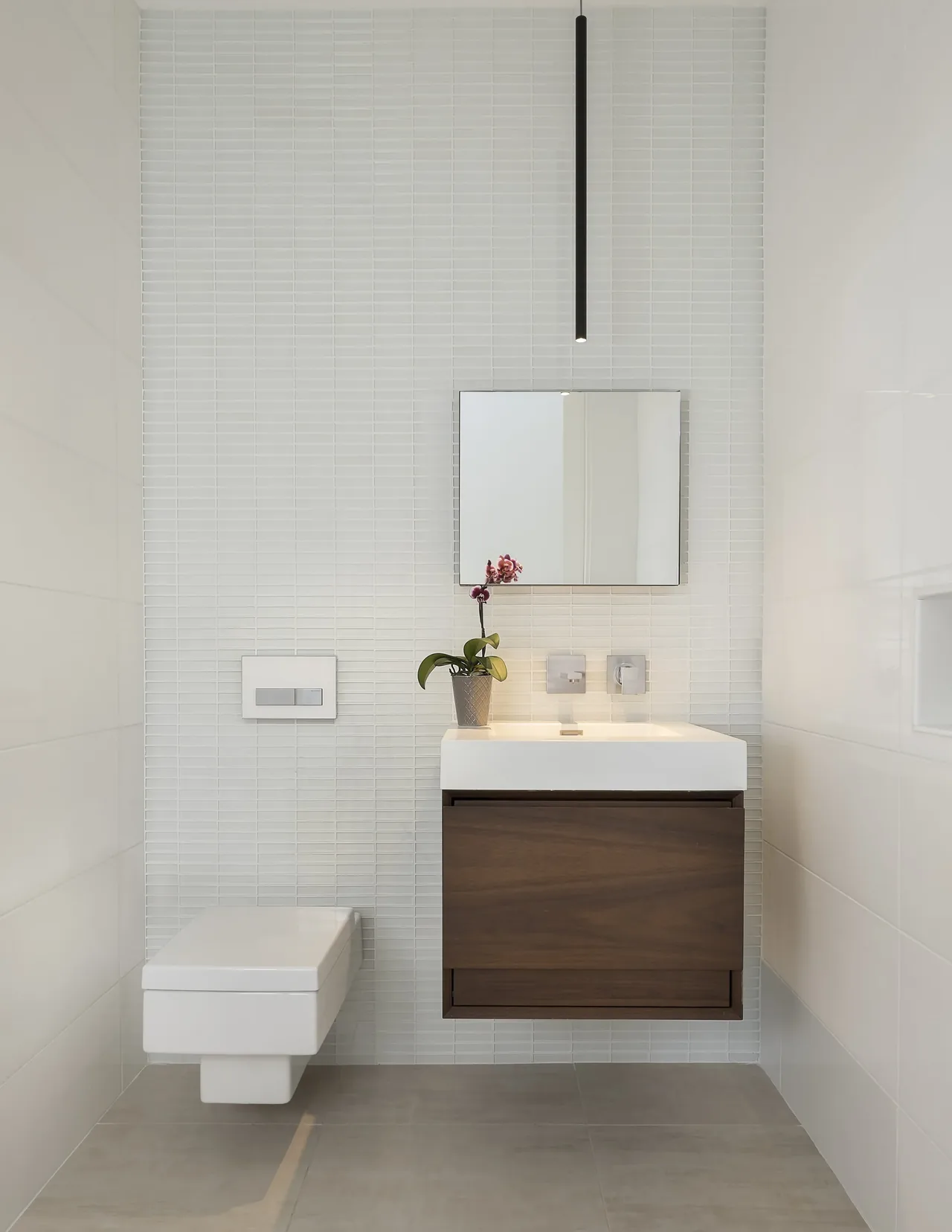 Kim Residence bathroom features a wall-mounted toilet and a floating wooden vanity with a rectangular sink.