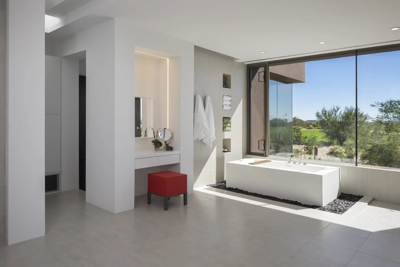 The Kim Residence bathroom features a rectangular soaking tub beside expansive windows with desert views.