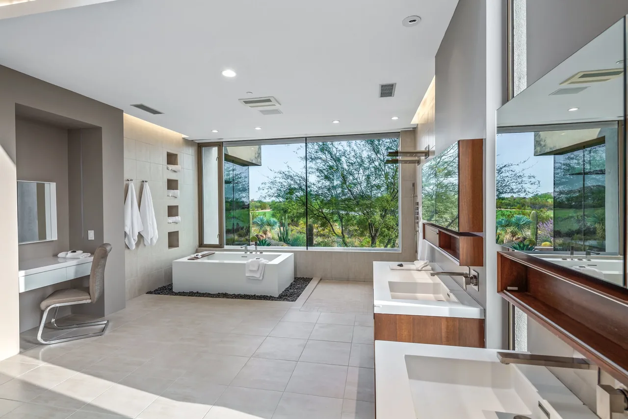 Kim Residence bathroom by Tate Studio Architects features dual sinks and a freestanding tub with a desert landscape view.