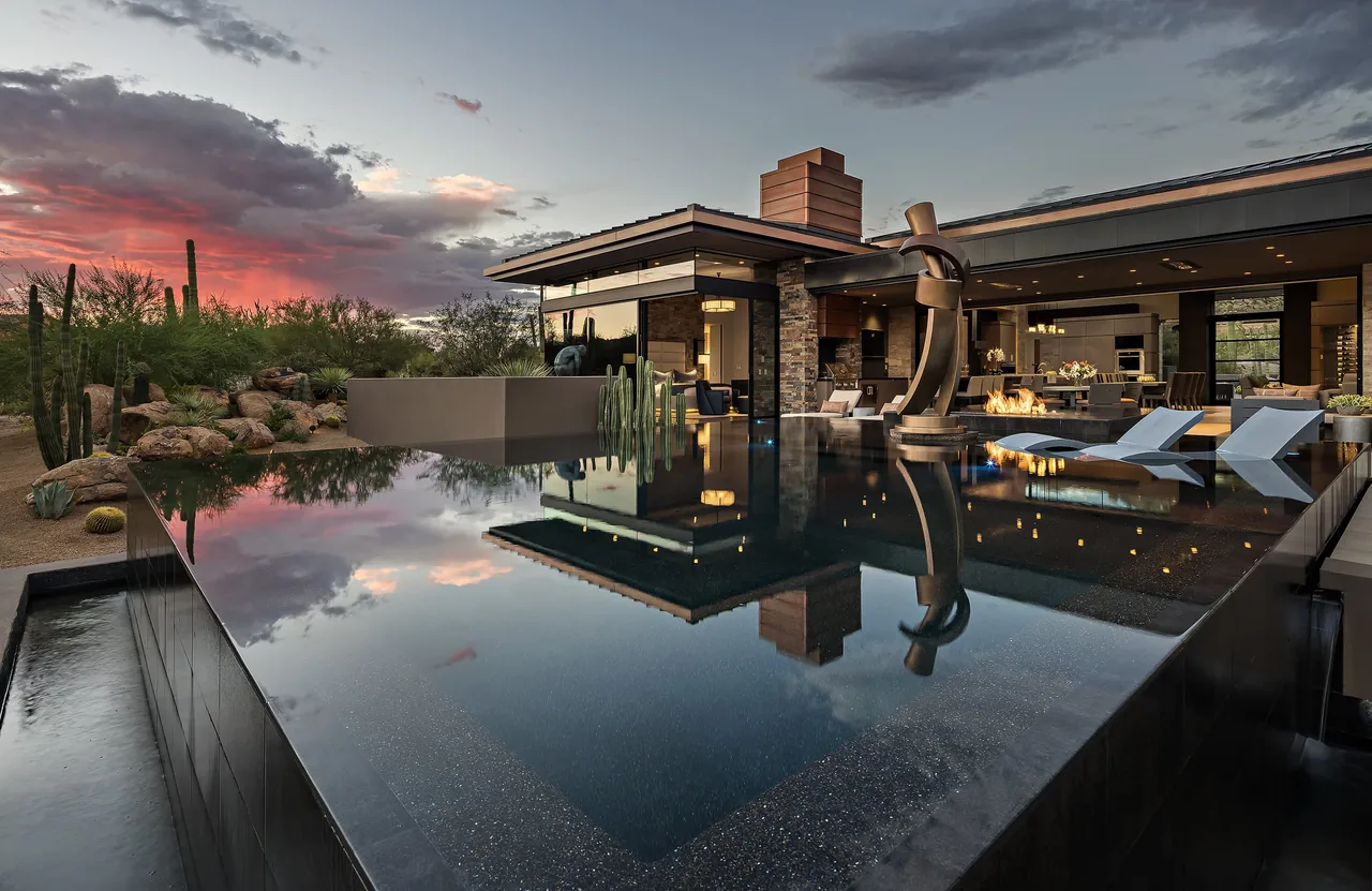 Silversmith Residence features a modern exterior with an infinity pool reflecting the desert landscape at sunset.