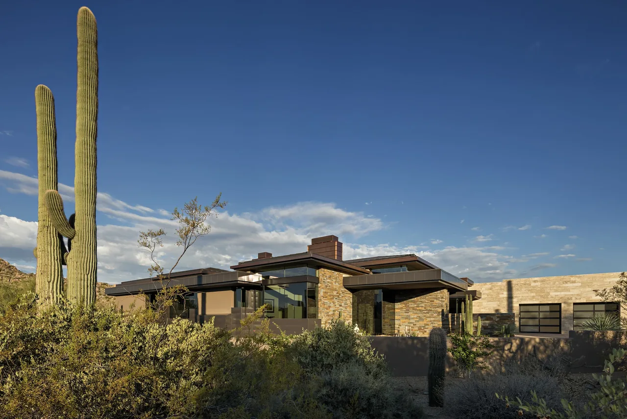 Silversmith Residence features a flat roof and textured stone exterior walls amidst desert landscaping.