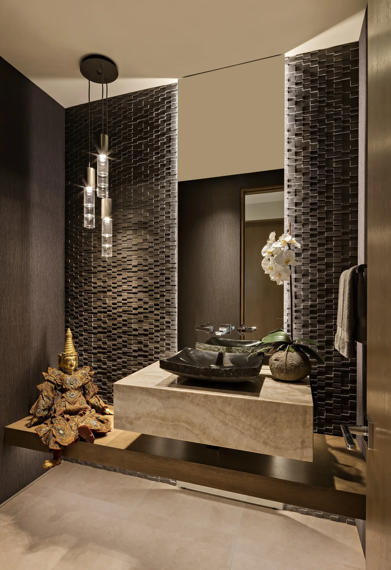 This bathroom features a floating stone vanity with a sculptural vessel sink, textured tile walls, and three pendant lights.