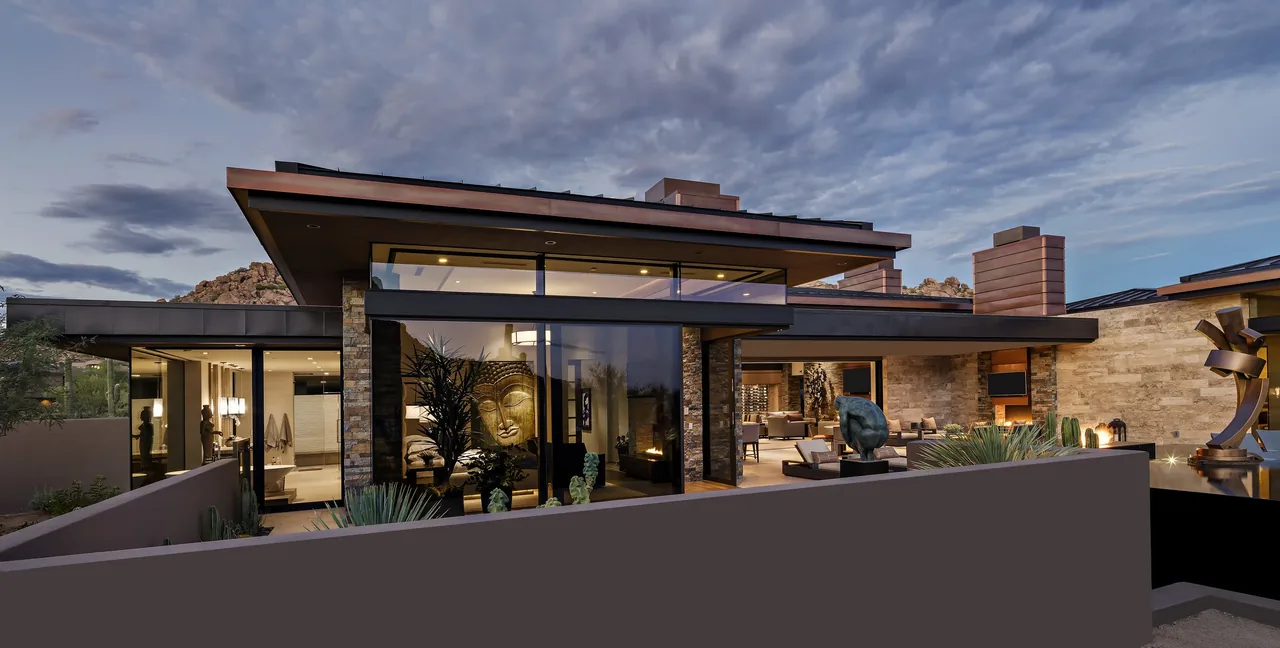 Exterior front view of the Silversmith Residence showing stone walls, expansive glazing, and outdoor seating spaces.