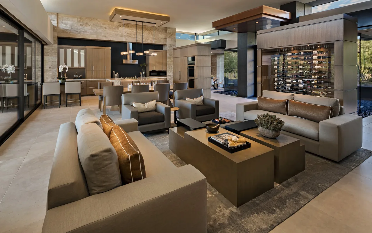Open living and kitchen area featuring a stone kitchen island, leather chairs, and a visible wine storage display at Silversmith Residence.