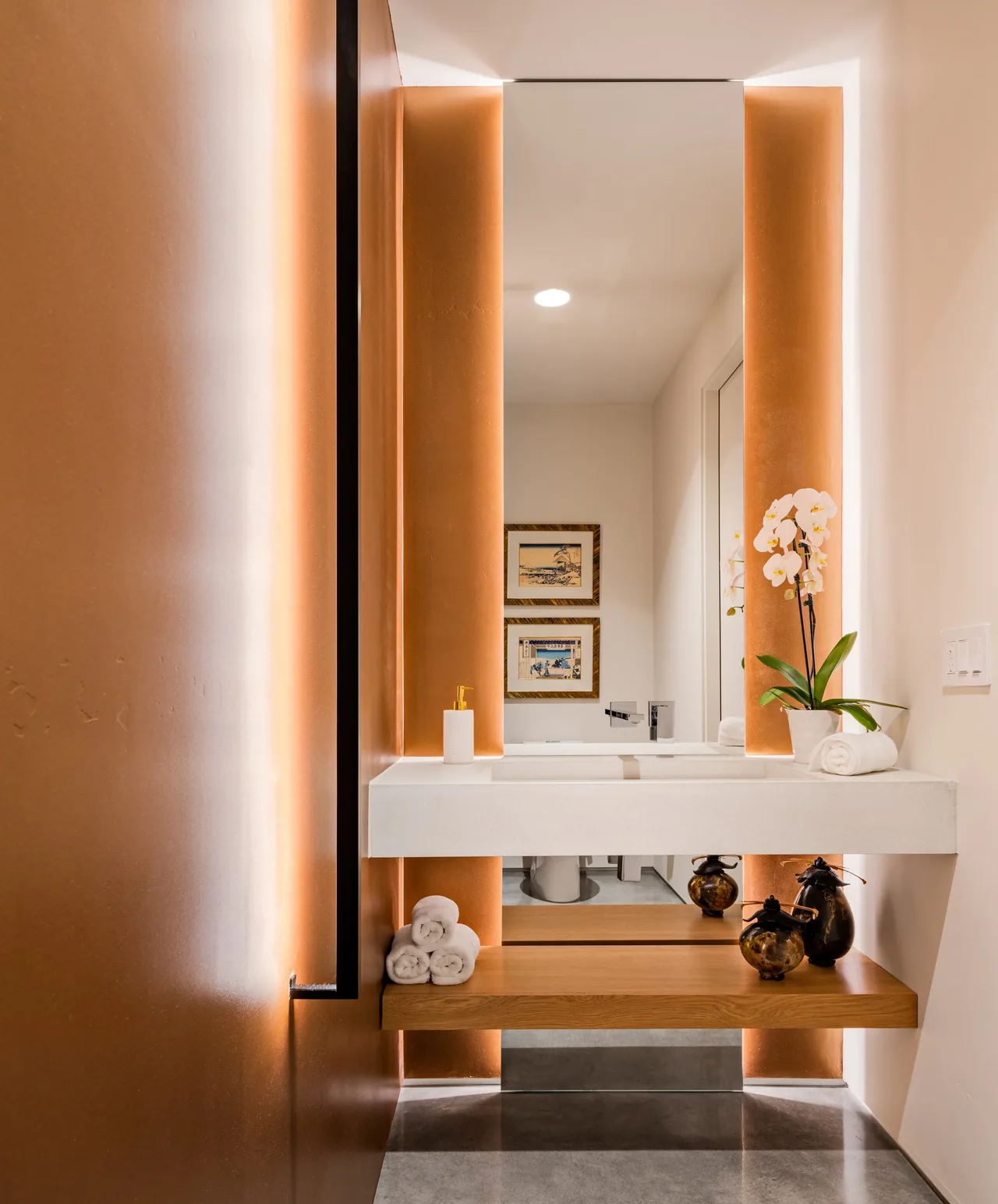 Shea-Naito Residence bathroom features a backlit mirror and floating wooden shelf with decorative items.