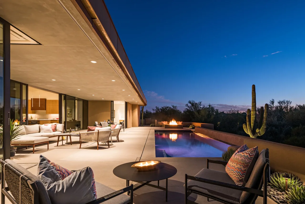 The Shea-Naito Residence features an outdoor living area with pool, fire pit, and seating under an extended flat roof at sunset.