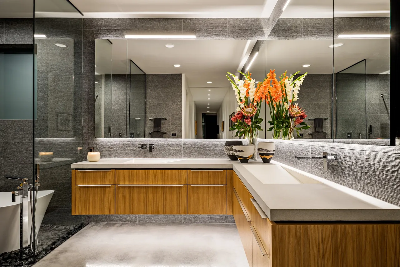 Shea-Naito Residence bathroom features a floating wood vanity with integrated sinks and a large mirror by Tate Studio Architects.
