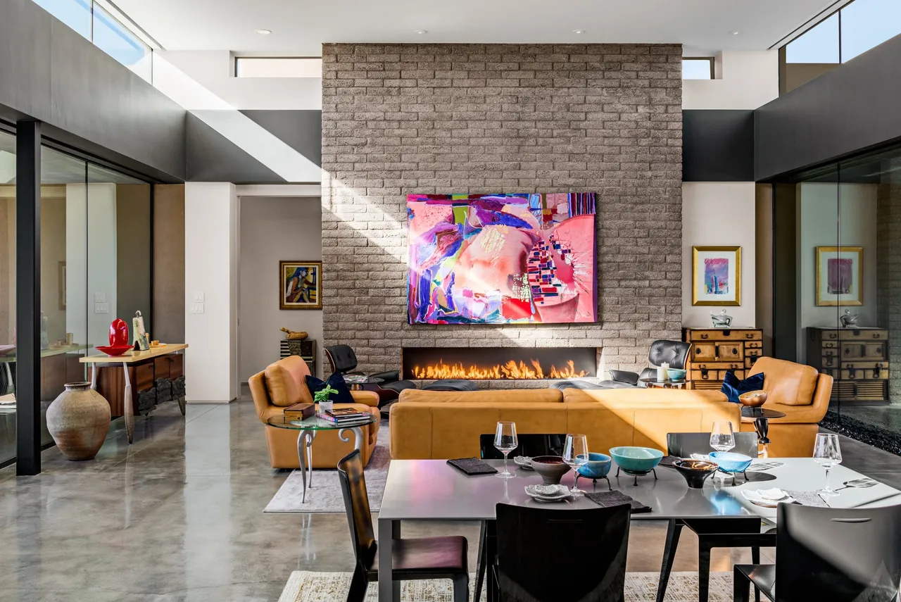 The Shea-Naito Residence living area features a floor-to-ceiling brick fireplace with modern seating and abstract artwork.