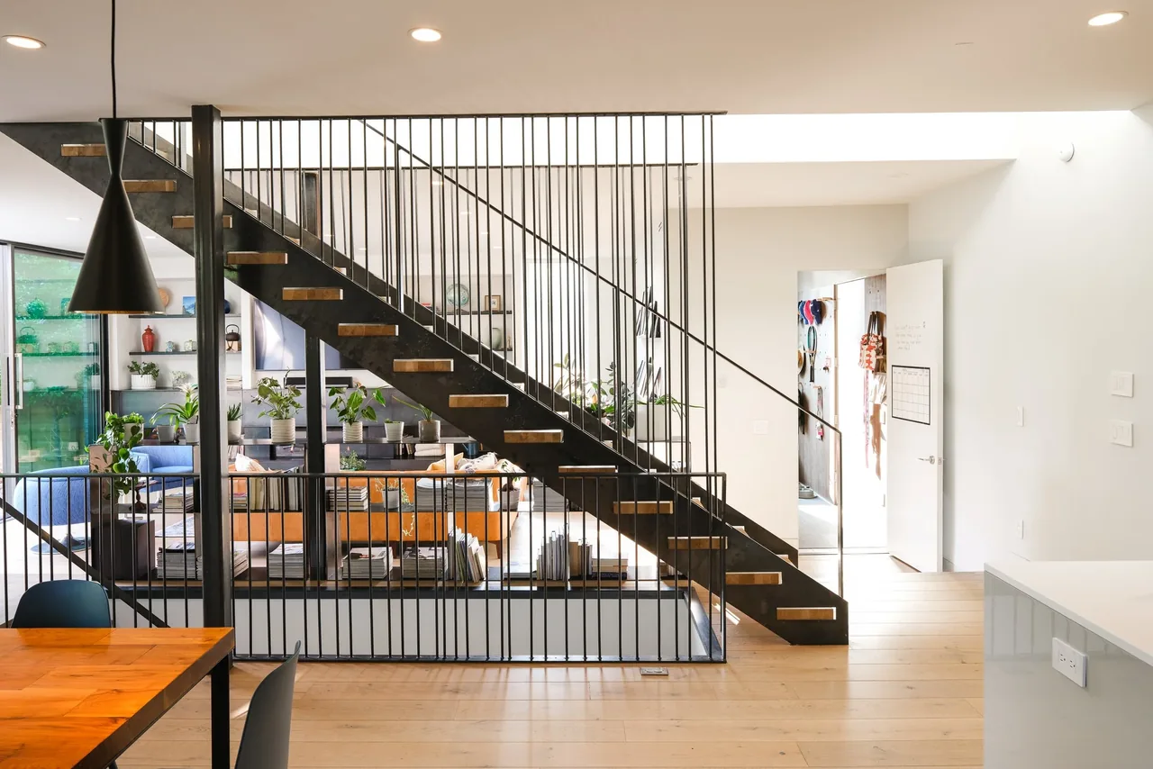 THE LOCUST HOME showcases a floating metal staircase that visually divides the open living and dining spaces.