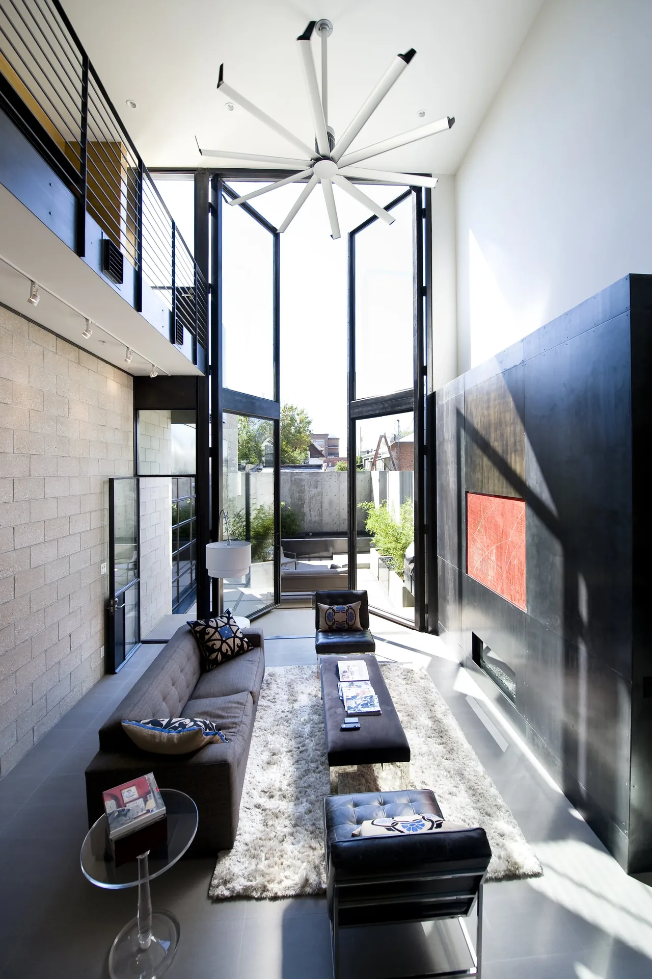 Bright modern living room with floor-to-ceiling windows and black metal accent wall housing a fireplace.