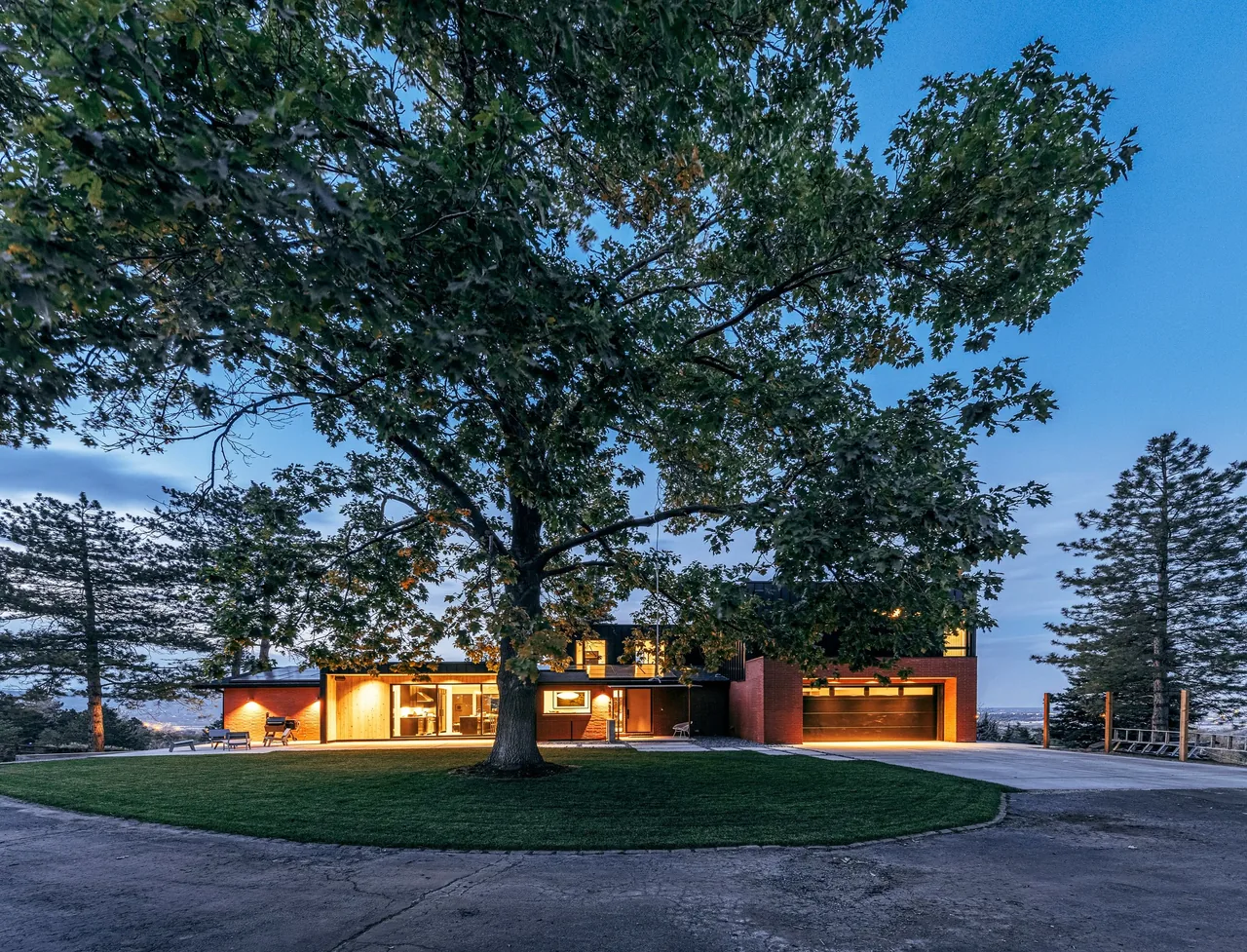 Modern house exterior at dusk featuring large windows and an attached garage.