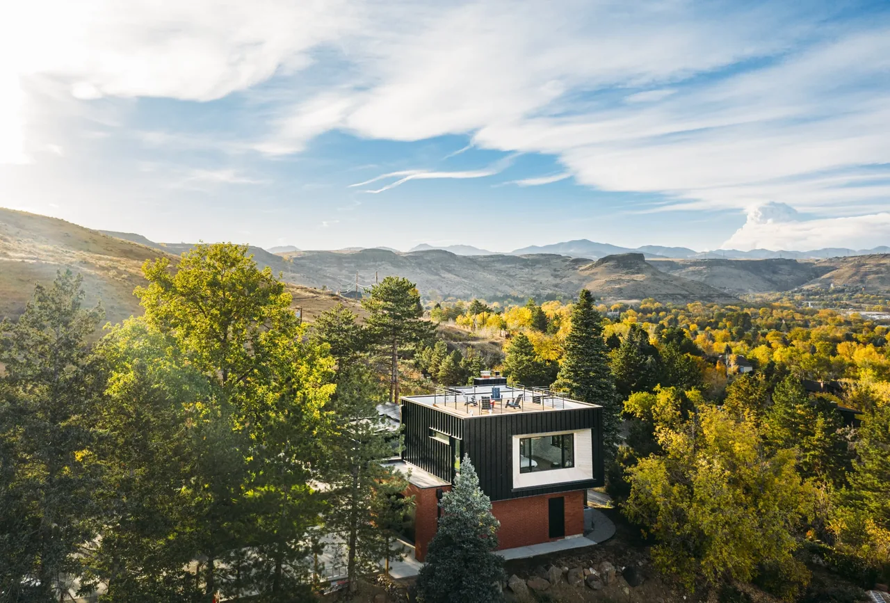 The Foothill project by DAVIS URBAN features a modern house with rooftop deck set in a forested hillside with expansive hill views.