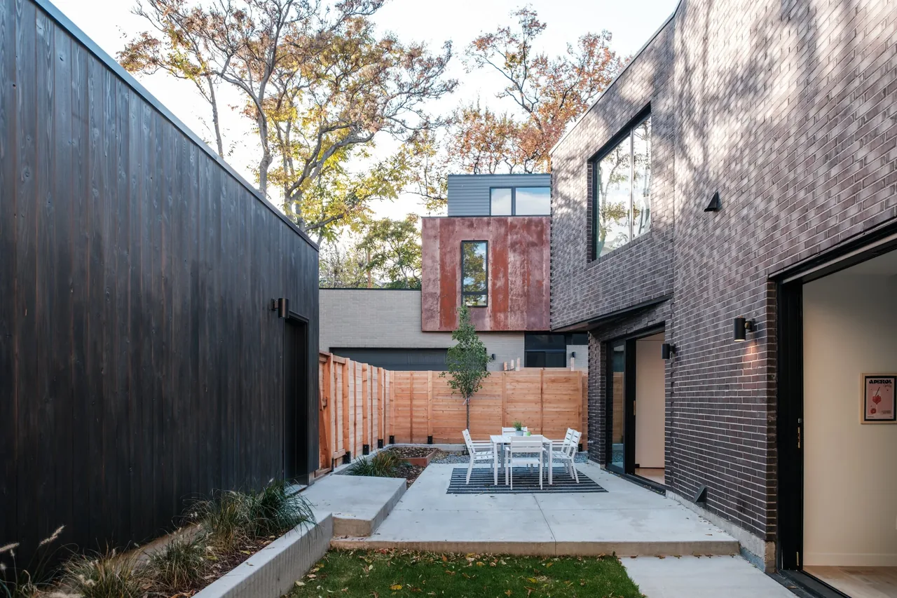 Exterior courtyard area features a concrete patio with a white dining set and dark brick and wood siding.