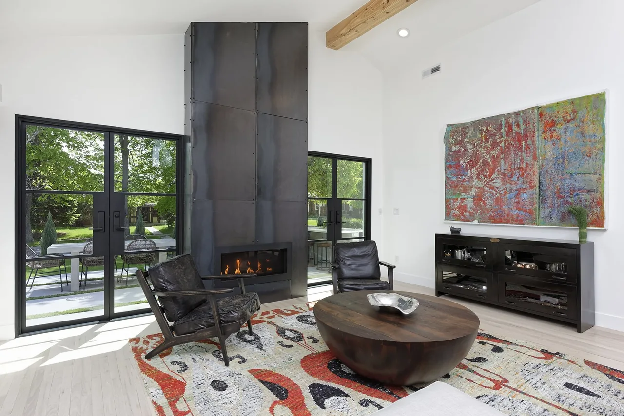 Living room with blackened steel fireplace, vertical window grid, and black window frames.