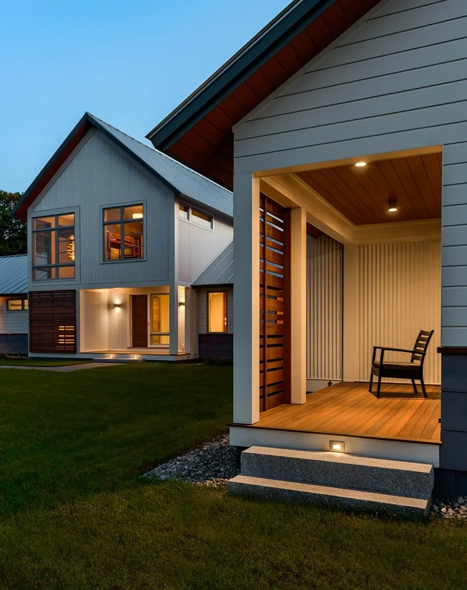 Meadow Retreat by Smith & Vansant Architects shows a modern house with exterior lighting and a covered porch with wood slat screens.