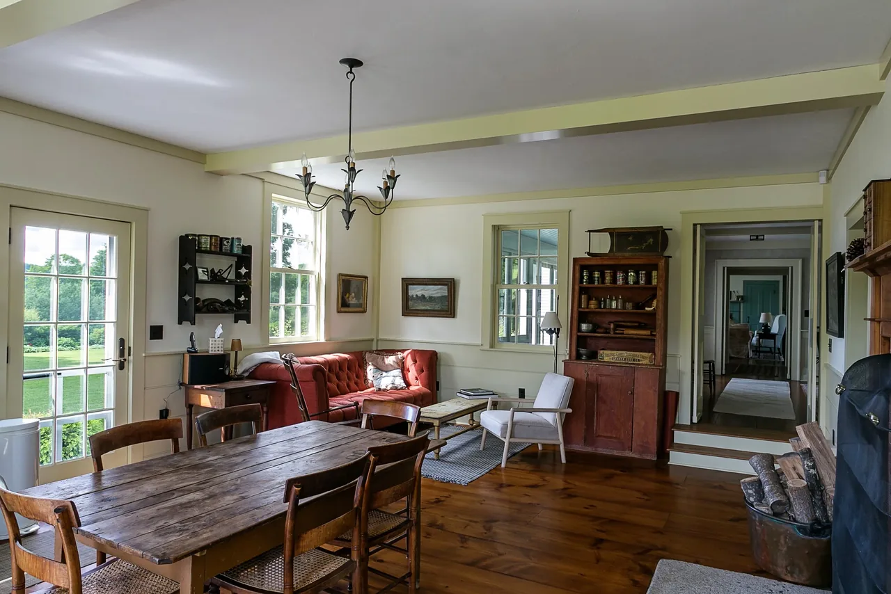 Dining and living area in Corinth Retreat with rustic wooden furniture, vintage decor, and a wrought iron chandelier.